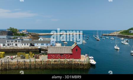 Vista aerea del Motif Number 1, una vivace baracca rossa per la pesca, in contrasto con il tranquillo porto blu e l'oceano punteggiato di barche. Rockport, Massachusetts Foto Stock