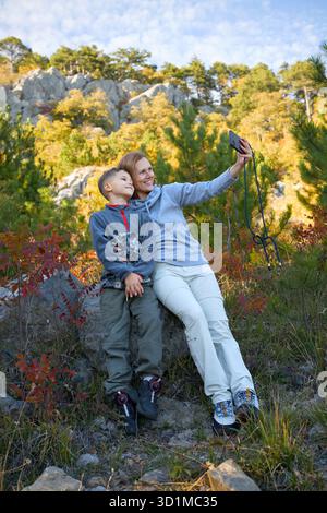 Madre e figlio portano Selfie nella foresta di montagna autunnale Foto Stock