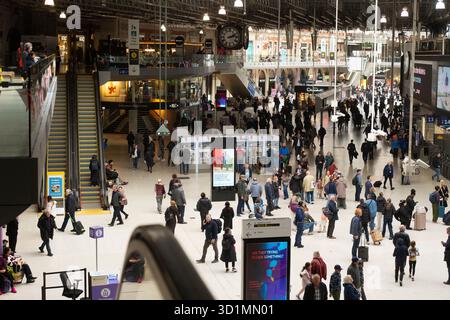 Gli affollati pendolari della stazione Waterloo di Londra, un importante snodo dei trasporti, attraversano l'atrio per i loro viaggi. Foto Stock