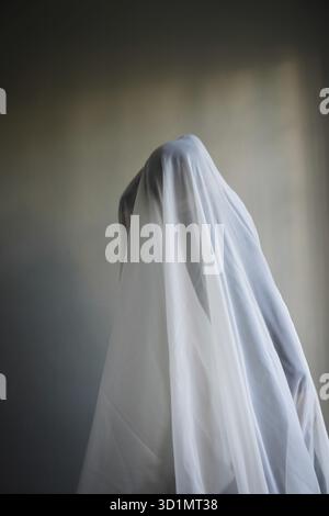 Donna con un panno bianco largo, costume fantasma Foto Stock