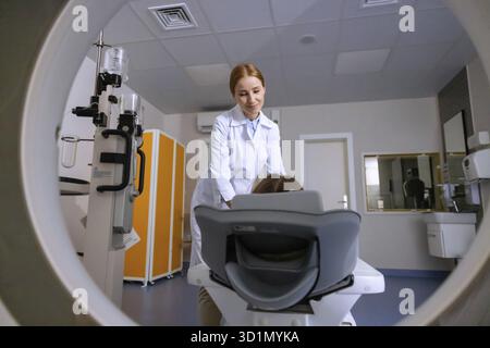 Medico donna che conduce la risonanza magnetica della persona, facendo tomografia, esaminando la salute del paziente in clinica moderna Foto Stock