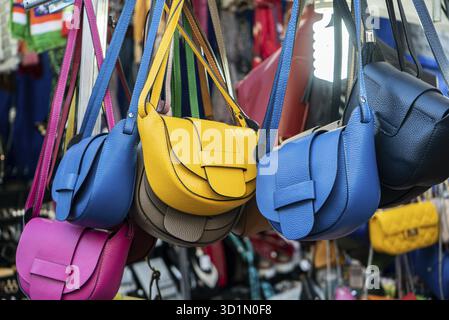 Molte borse in pelle colori vivaci appesi in mostra nel mercato della strada dello shopping Foto Stock