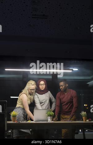 Tre gli imprenditori aventi la discussione su computer portatile in ufficio Foto Stock