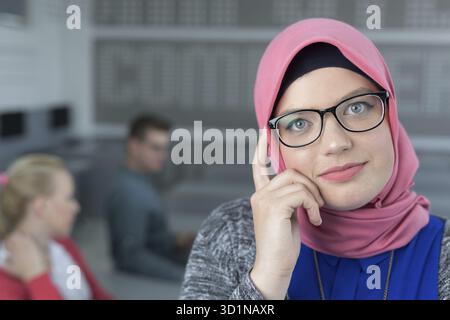Giovane donna islamica con un gruppo di studenti vestiti con abiti tradizionali all'interno dell'ambiente scolastico Foto Stock