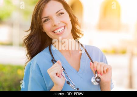 Ritratto di giovane femmina adulta medico o infermiere indossando scrubs e stetoscopio al di fuori. Foto Stock