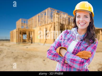 Giovane e attraente lavoratrice edile che indossa guanti, elmetto e occhiali di protezione presso il cantiere edile Foto Stock