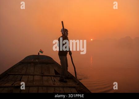 Uomo locale che si muove in barca sul fiume Yamuna con un palo all'alba, Agra, Uttar Pradesh, India Foto Stock