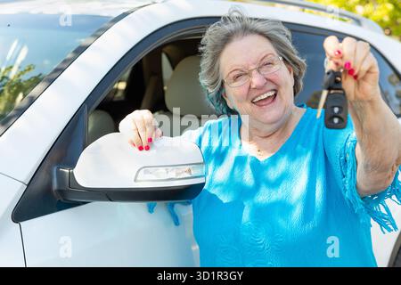 Donna anziana felice con nuova auto e chiavi Foto Stock