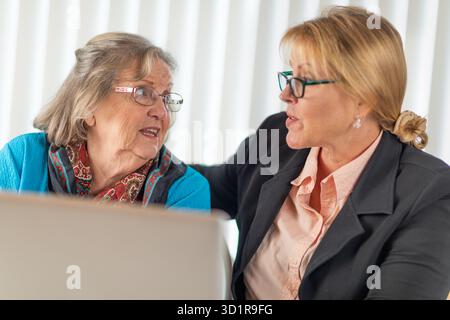 Donna che aiuta Senior Adult Lady su un computer portatile Foto Stock