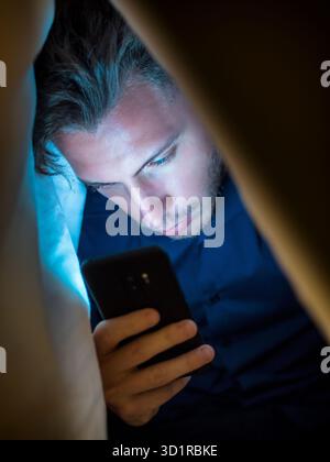 Giovane che si nasconde mentre usa un telefono cellulare Foto Stock