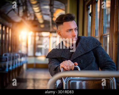 Giovane uomo a cavallo su tram o bus vecchio in città Foto Stock