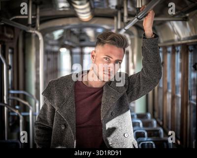Giovane uomo a cavallo su tram o bus vecchio in città Foto Stock