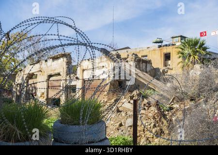 Filo spinato e una sentinella post con le bandiere in background in zona cuscinetto delle Nazioni Unite (linea verde) in divisa Nicosia, capitale dell'isola di Foto Stock