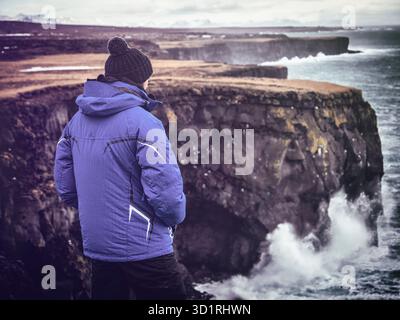 Viaggiatore maschile che guarda il mare tempestoso dalla scogliera Foto Stock