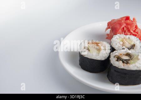 Primo piano di tre panini di sushi su un piatto piccolo e molto spazio per il testo a sinistra Foto Stock
