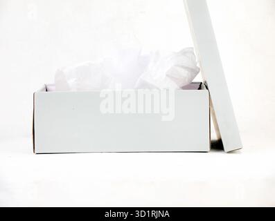 Confezione regalo bianca aperta dal design minimalista con carta velina su sfondo pulito Foto Stock