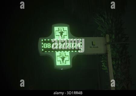 Marrakesch, Marrakesch-Safi - Marocco - 08-14-2024: Un segno a croce LED verde che mostra il 08/22/2024 e i simboli medici in una farmacia, con un BL PL bianco Foto Stock