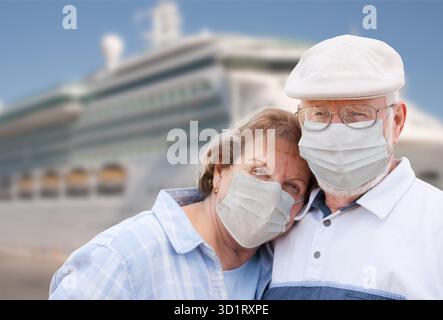 Coppia senior che indossa maschere facciali in piedi davanti alla nave da crociera passeggeri Foto Stock