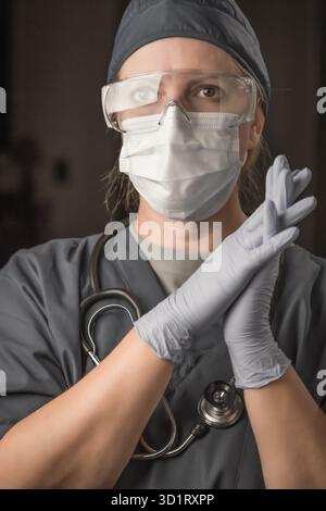 Medico o infermiera donna che indossa scrub, maschera protettiva per il viso e occhiali di protezione Foto Stock