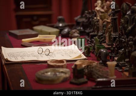 La sedia e gli occhiali di Sigmund Freud sulla scrivania di studio dello psicoanalista della sua casa a nord di Londra, il 29 ottobre 2025, a Londra, Inghilterra. Lo psicoanalista Sigmund Freud (1865-1939) visse qui al 20 Maresfield Gardens di Hampstead dopo essere fuggito dall'Austria annessa ai nazisti - ma dopo la sua morte, appena un anno dopo, fu sua figlia Anna Freud che continuò a lavorare qui nella psicologia infantile psicoanalitica fino alla sua morte nel 1982. Il Museo Freud contiene l'archivio Freud di libri e manufatti antichi dei viaggi di Sigmund Freud che egli fu in grado di portare intatto quando fu costretto a fuggire prima di lui Foto Stock