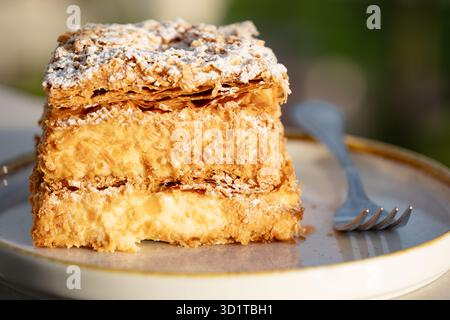 Grecia. Una fetta di una crema mille-feuille o di una crema di pasticceria Napoleone o di una fetta di crema pasticcera. La torta viene servita su un piatto con una forchetta Foto Stock