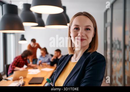Donna d'affari bionda sicura di sé che guida il team in un ambiente moderno per l'ufficio. Foto Stock