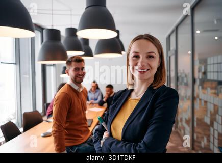 Donna d'affari bionda sicura di sé che guida il team in un ambiente moderno per l'ufficio. Foto Stock