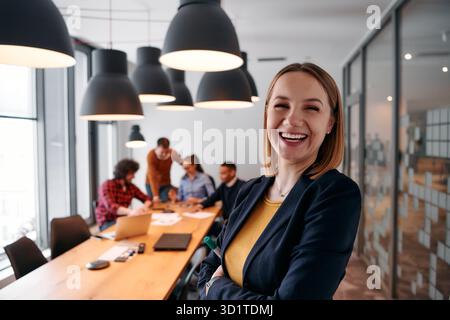Donna d'affari bionda sicura di sé che guida il team in un ambiente moderno per l'ufficio. Foto Stock