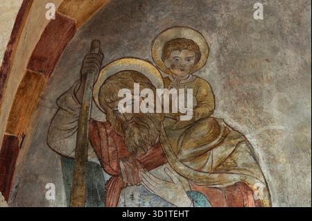 Cristo bambino detiene il simbolo globus cruciger e fa un gesto di benedizione mentre San Cristoforo lo porta attraverso il fiume: Dettaglio della pittura murale dei primi anni '1200 in tardo romanico e primo gotico Sankt-Georgs-Dom o Limburger Dom cattedrale a Limburg an der Lahn, Assia, Germania. Tra le tante opere murali ricoperte di bianco nel 1749 ma ora restaurate nel rispetto delle sue origini medievali. Foto Stock