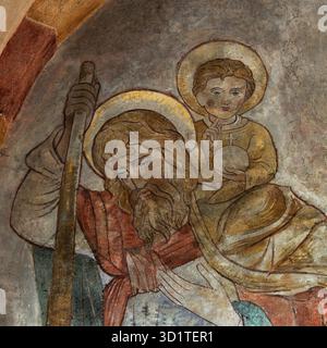 Cristo bambino fa un gesto di benedizione e tiene in mano il simbolo globus cruciger mentre San Cristoforo lo porta attraverso il fiume: Dettaglio della pittura murale dei primi anni '1200 in tardo romanico e primo gotico Sankt-Georgs-Dom o Limburger Dom cattedrale a Limburg an der Lahn, Assia, Germania. Tra le tante opere murali ricoperte di bianco nel 1749 ma ora restaurate nel rispetto delle sue origini medievali. Foto Stock