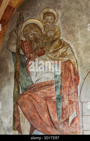 San Cristoforo porta il bambino Cristo - e l'onere aggiuntivo dei peccati del mondo - attraverso un fiume: Dettaglio quasi completo della pittura murale dei primi anni '1200 del secolo d C nel tardo romanico e nel primo gotico Sankt-Georgs-Dom o nella cattedrale Limburger Dom a Limburg an der Lahn, Assia, Germania. Tra le tante opere murali ricoperte di bianco nel 1749 ma ora restaurate nel rispetto delle sue origini medievali. Foto Stock