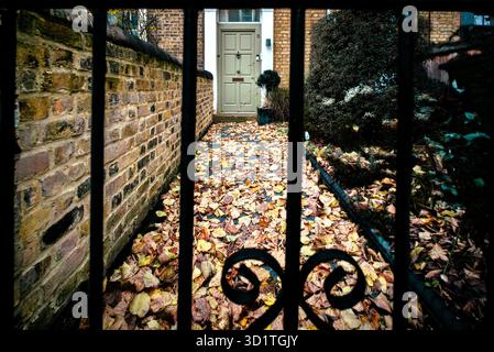 L'autunno parte sul sentiero che porta all'ingresso, visto attraverso il cancello Foto Stock