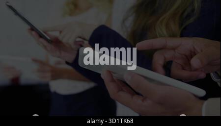 Un gruppo di quattro professionisti in abbigliamento da lavoro che toccano tablet e telefoni nella sala riunioni Foto Stock