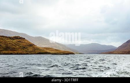 Spettacolare paesaggio costiero nel Connemara, Irlanda, con aspre montagne, acque atlantiche battute dal vento e cieli tranquilli lungo la Wild Atlantic Way. Foto Stock