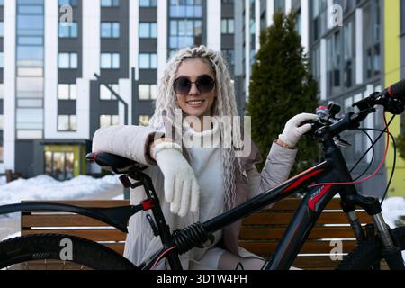 Donna seduta sulla panchina accanto a Bike Foto Stock