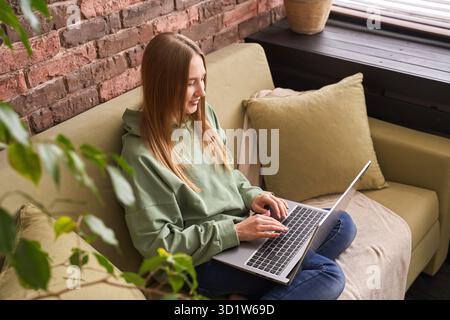 Giovane donna che lavora in ambienti chiusi. Casa vacanza ritratto. Blogger video editing Foto Stock