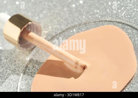 Campione di texture beige. Goccia di crema con scintille d'argento. Cura della pelle per il viso Foto Stock