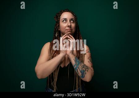 Donna con Dreadlock in piedi davanti allo sfondo verde Foto Stock