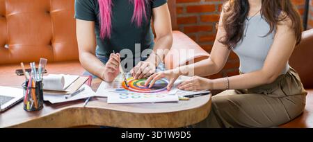 LGBTQ+ transgender uomo bello autentico Specialista con capelli rosa e trans non binari che lavorano insieme Design in cr Foto Stock