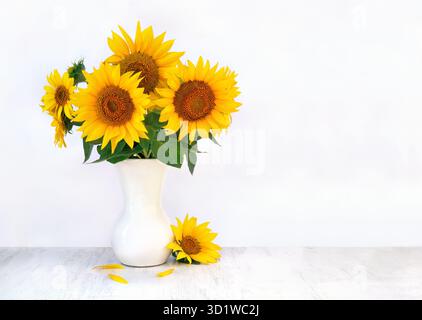 Bouquet di fiori gialli girasole in vaso di porcellana su un tavolo di legno bianco su sfondo chiaro con spazio per il testo Foto Stock