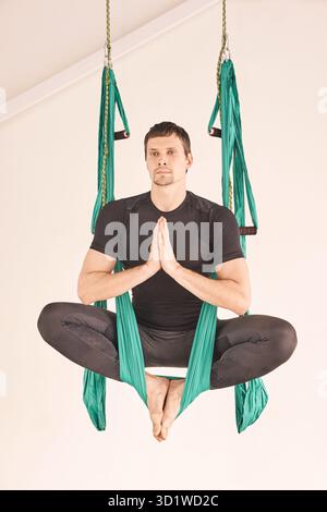 Persona maschile fare amaca yoga lezione di esercizio. Meditazione in aria calma Foto Stock
