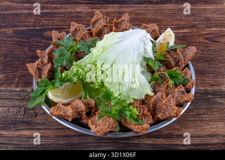 Kofte CIG o polpette crude su fondo di legno. Delizioso cibo turco tradizionale; nome turco; cig kofte (polpetta cruda in turco) con lattuga. Foto Stock
