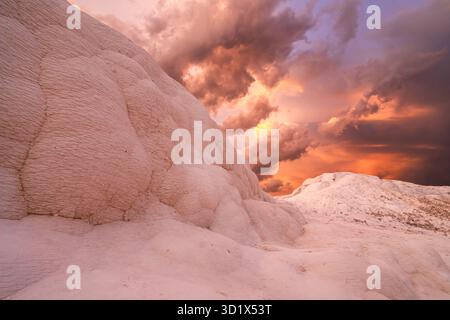 Tramonto spettacolare sulle bianche terrazze in travertino di Pamukkale, Türkiye (Turchia), sotto nuvole tempestose. Foto Stock