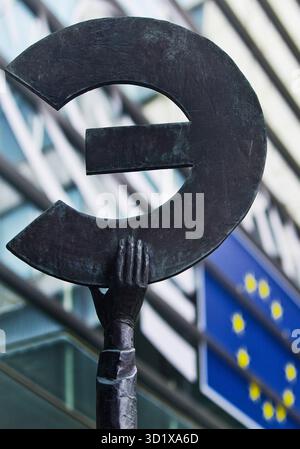 Simbolo dell'euro di fronte alla bandiera dell'Unione europea, al Parlamento europeo, a Bruxelles, all'Europa Foto Stock