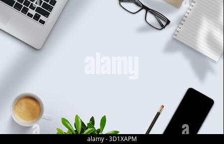 Laptop, notebook, caffè, pianta e smartphone disposti su una scrivania luminosa con ombre naturali, che rappresenta un moderno spazio di lavoro digitale Foto Stock