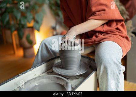 Ceramista femmina che forma pareti di vaso su ruota di ceramica rotante, formando argilla in forma Foto Stock