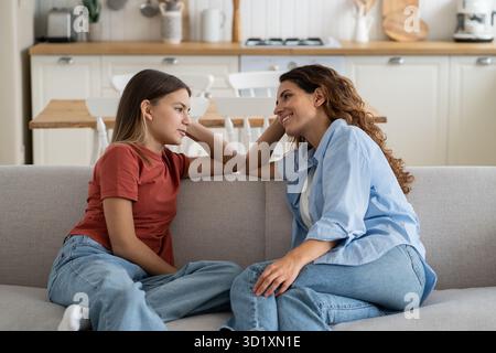 Una donna carismatica felice che parla con una ragazza adolescente di amici di scuola siede sul divano in casa Foto Stock