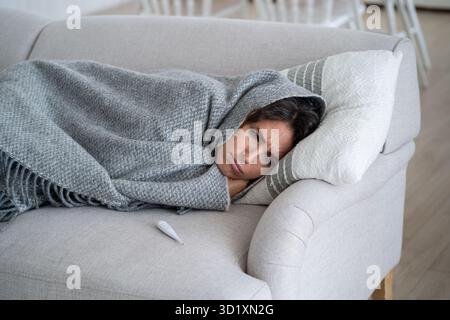 Giovane donna malata che soffre di febbre con brividi e brividi, sentendosi infelice e depresso Foto Stock