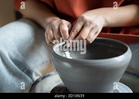 Hobby anti-stress, mani femminili che modellano argilla bagnata su ruota Foto Stock
