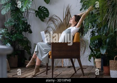 Calma italiana donna freelance giardiniere con occhi chiusi rilassarsi mentre al suo giardino accogliente casa Foto Stock
